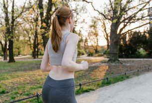 A woman jogs in a park during sunset, enjoying an outdoor fitness routine.
