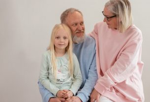 Grandparents lovingly embrace their granddaughter in a bright, studio setting, capturing family warmth and connection.