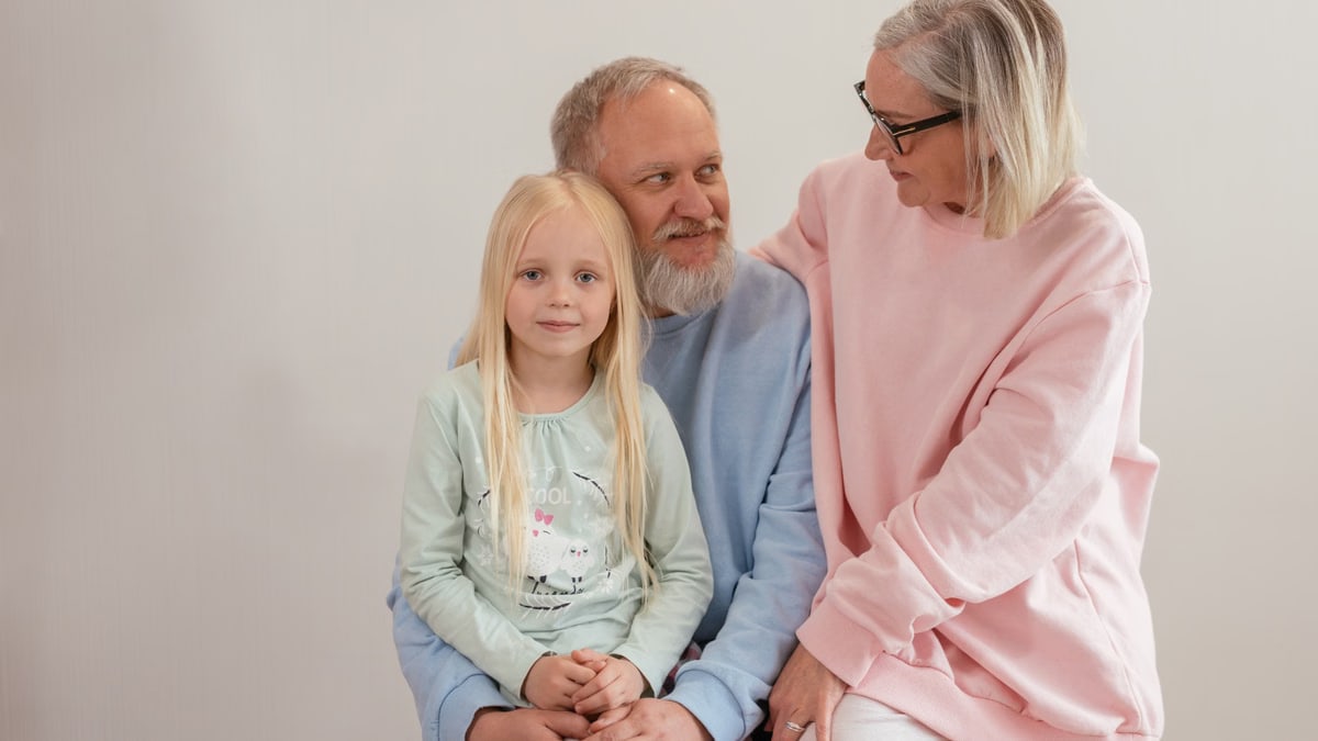 Grandparents lovingly embrace their granddaughter in a bright, studio setting, capturing family warmth and connection.